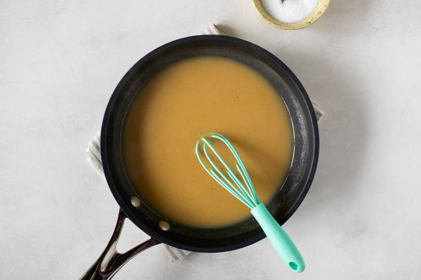 Gravy being whisked in a sauce pan.