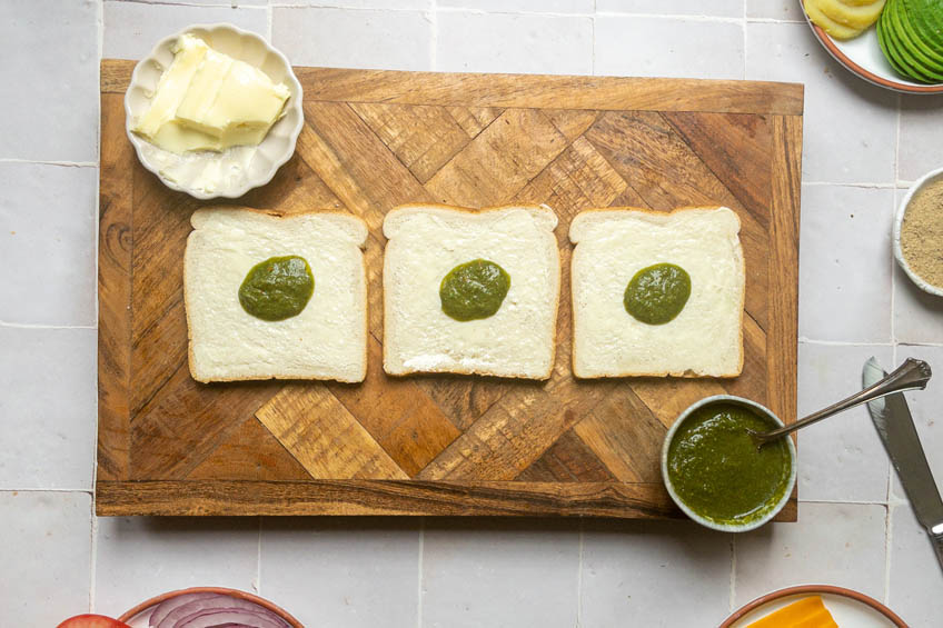 Buttered bread topped with green chutney for Bombay sandwiches