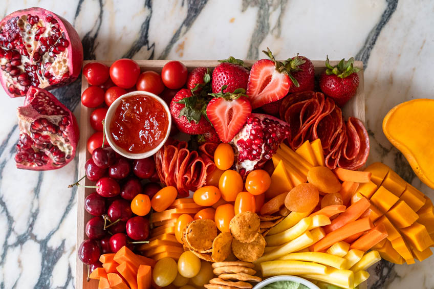 Red and orange ingredients on rainbow snack board