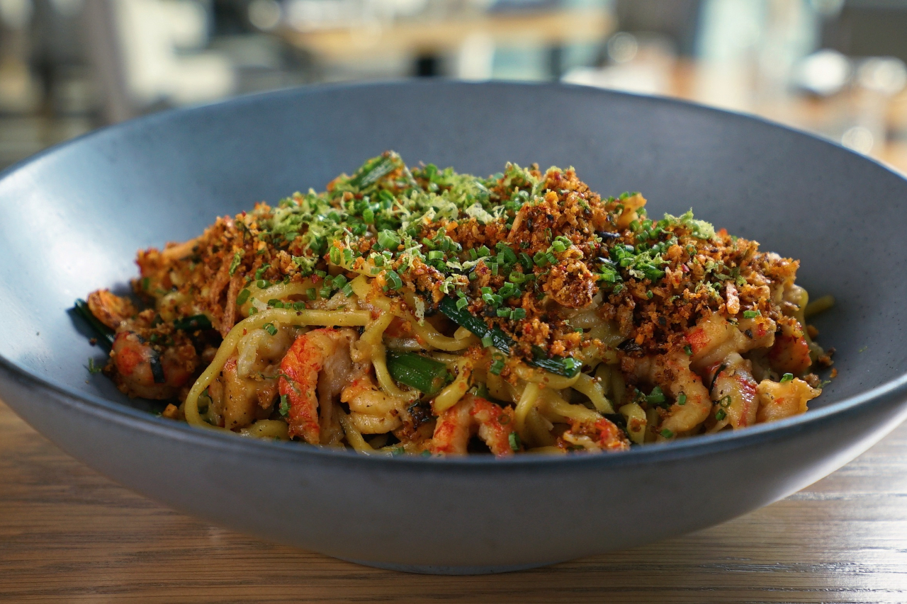 Bowl of stir-fried noodles with fresh herbs and crawfish