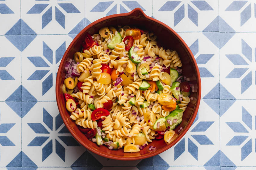 Ingredients for vegan pasta salad in a large bowl