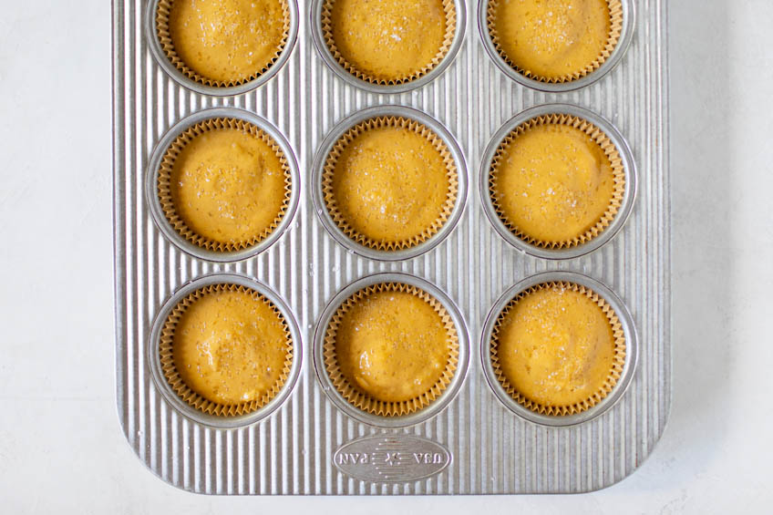 Muffin batter in muffin tins for pumpkin cream cheese muffins