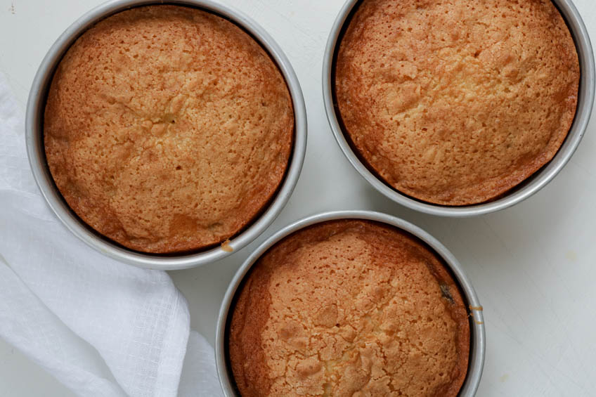 Three cakes cooling in cake pans