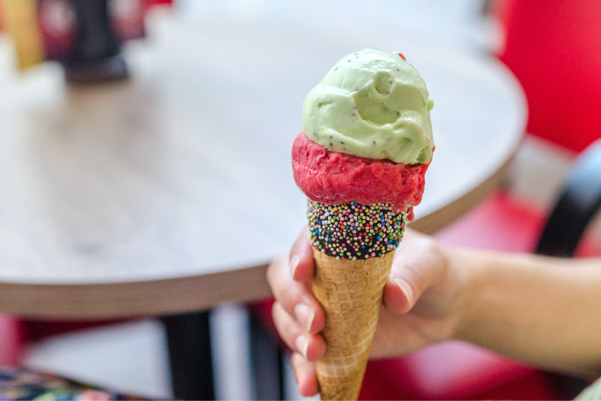 An ice cream cone with sprinkles and two scoops of pink and green ice cream