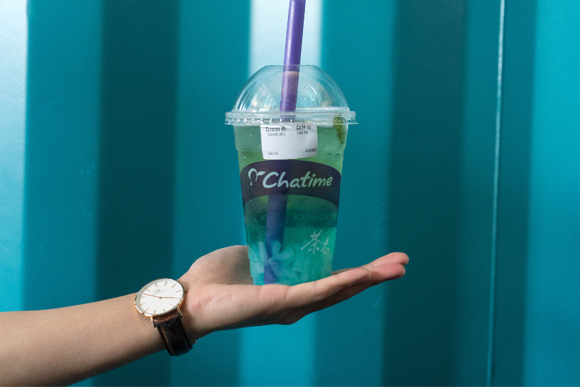 A hand holds a Chatime cup with a blue bubble tea