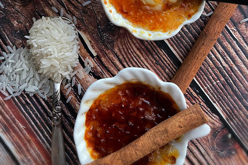 A small dish with a rice horchota creme brulee, a spoonful of dry rice beside