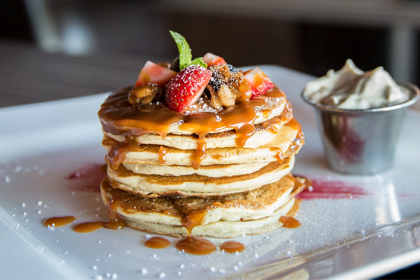 Generous stack of pancakes with syrup and berries