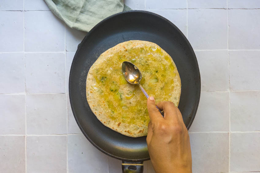 Aloo paratha being brushed with ghee