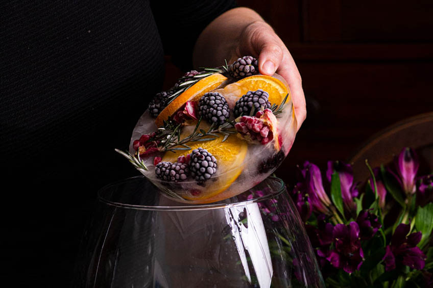 Frozen fruit disc being placed in a punch bowl