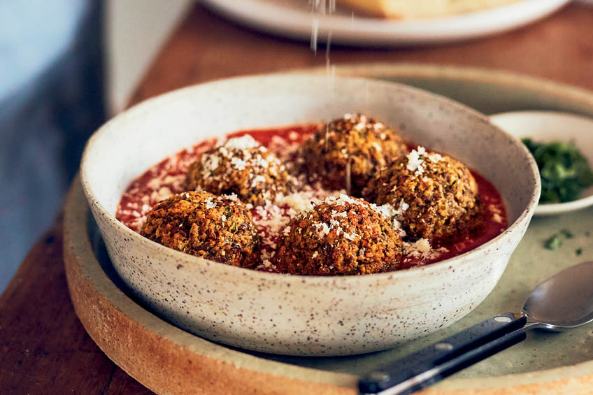 Meatless meatballs being sprinkled with cheese