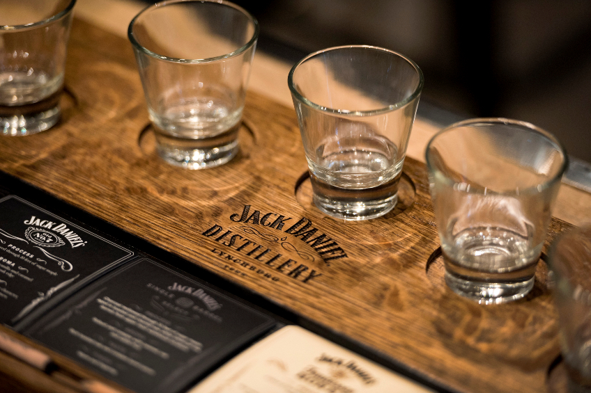 A whiskey flight with small glasses on a wooden tray