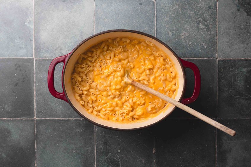 A red casserole dish with a large portion of vegan macaroni and cheese