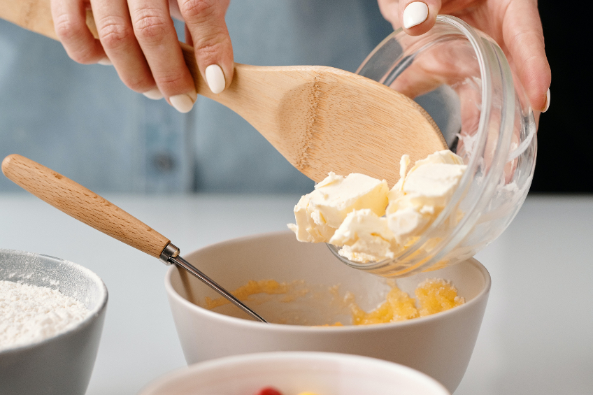 A woman adds butter to a baking bowl
