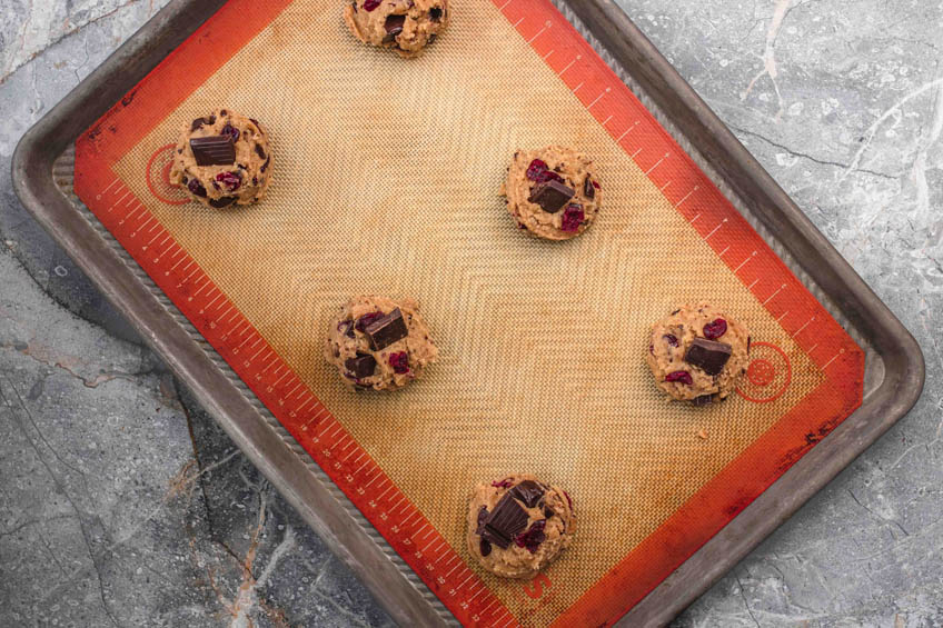 Dark chocolate cranberry cookie dough balls on a baking sheet