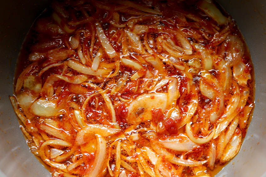 Tomato paste and onions simmering in a Dutch oven