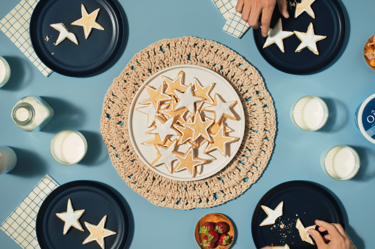 A tray of star-shaped sugar cookies surrounded by dark blue plates with cookies