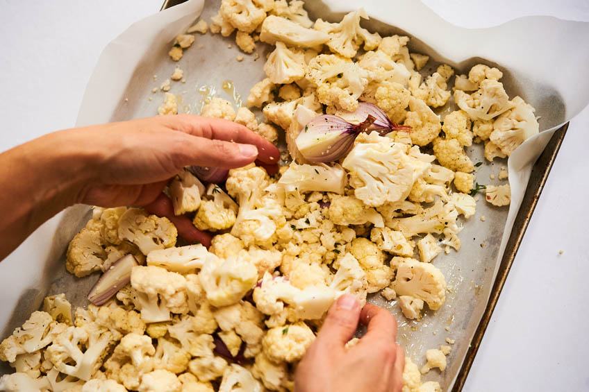 Cauliflower and shallots being tossed with olive oil and shallots