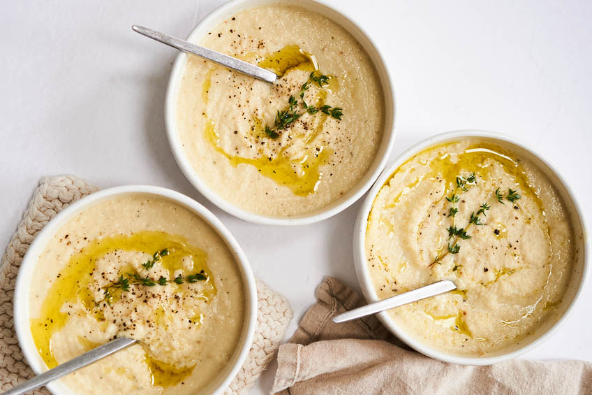 Roasted garlic and cauliflower soup in three bowls.