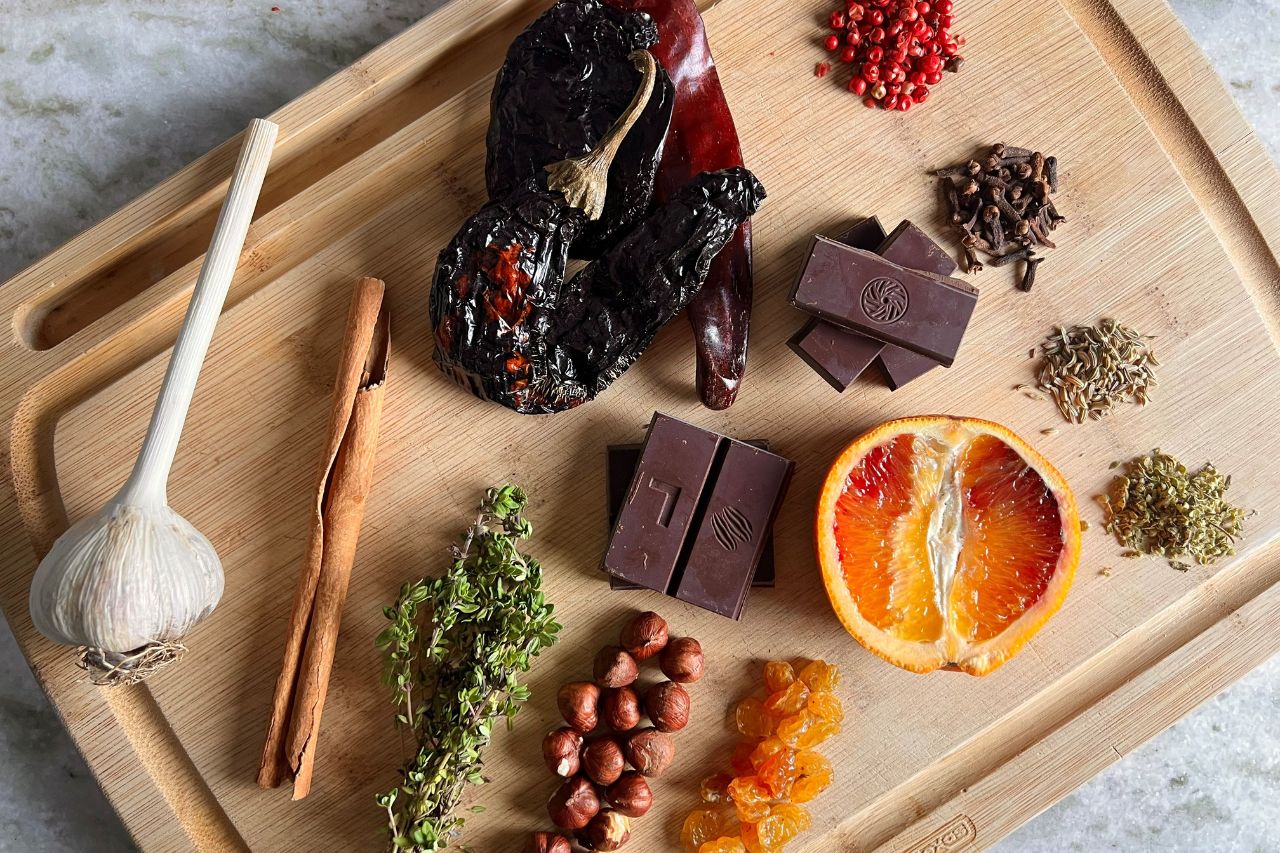 A flat lay of the ingredients for a spicy winter mole on a wooden cutting board