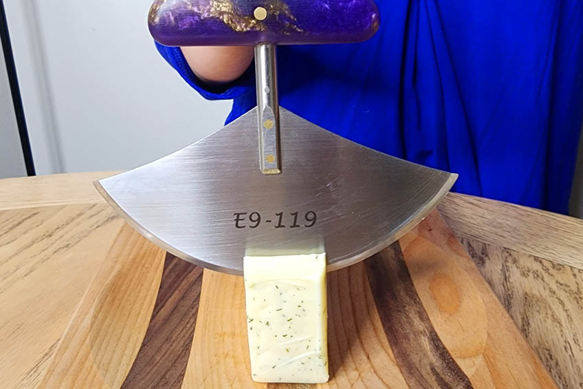 Cheese being cut with an ulu knife