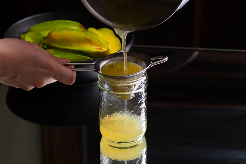 Starfruit syrup being drained into a jar