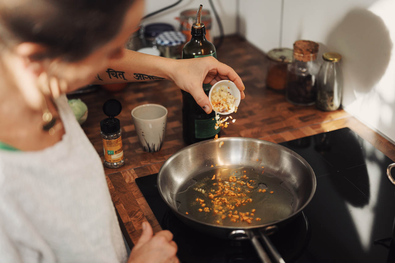 A person adding garlic to a pan