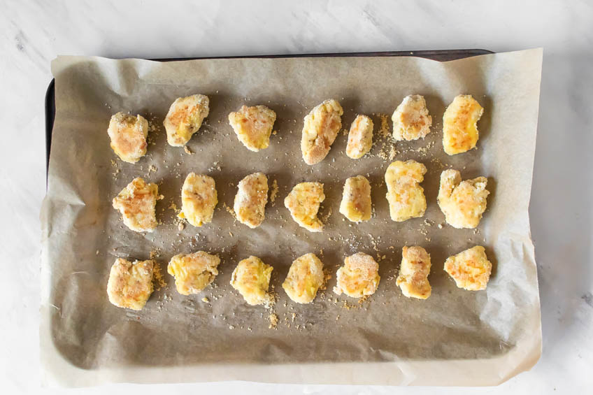 Baked chicken bites on a parchment-lined baking sheet