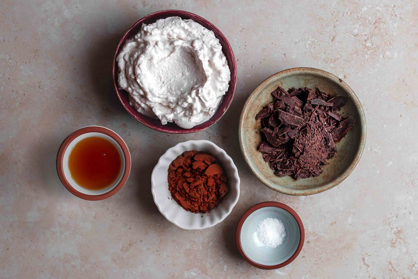 A flat lay of the ingredients needed for vegan hot chocolate: cocoa powder, dark chocolate, coconut, sugar