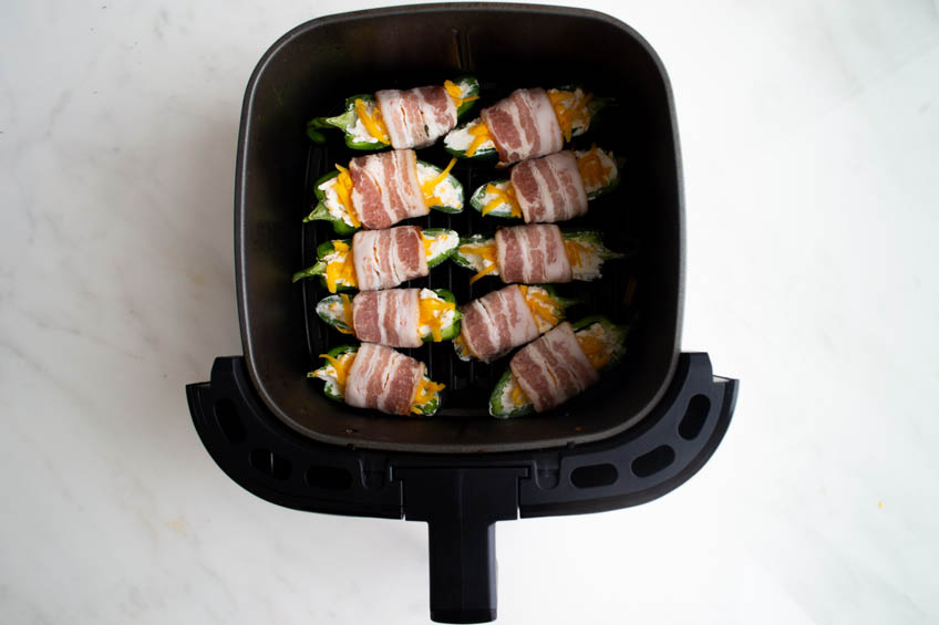 Uncooked jalapeno poppers in an air fryer basket