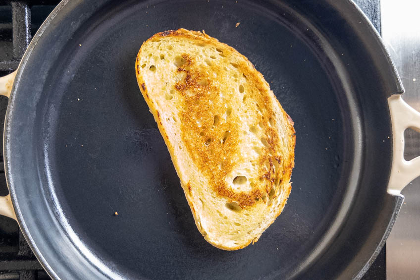 A piece of sourdough bread toasting in a skillet
