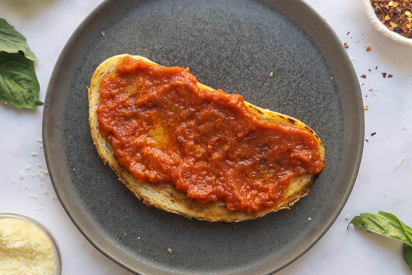 Sourdough toast topped with tomato sauce for Cottage Cheese Pizza Toast