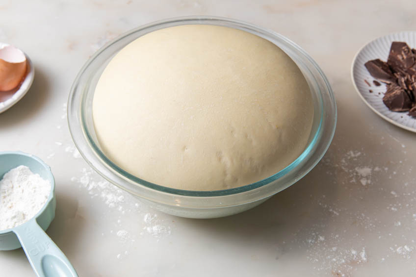 Sweet dough for hot cocoa buns in a glass bowl