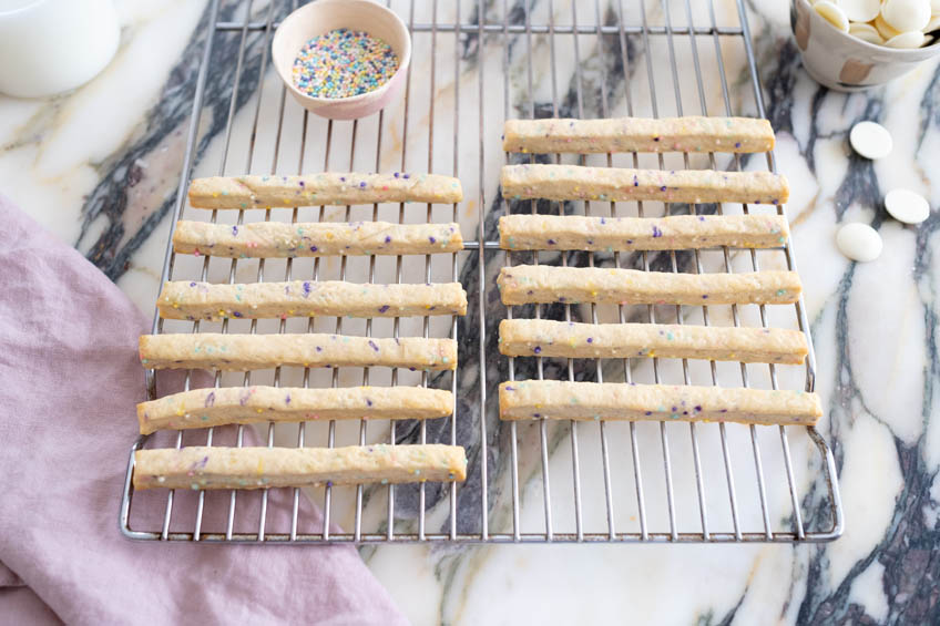 Birthday cake cookie sticks cooling on a wire rack