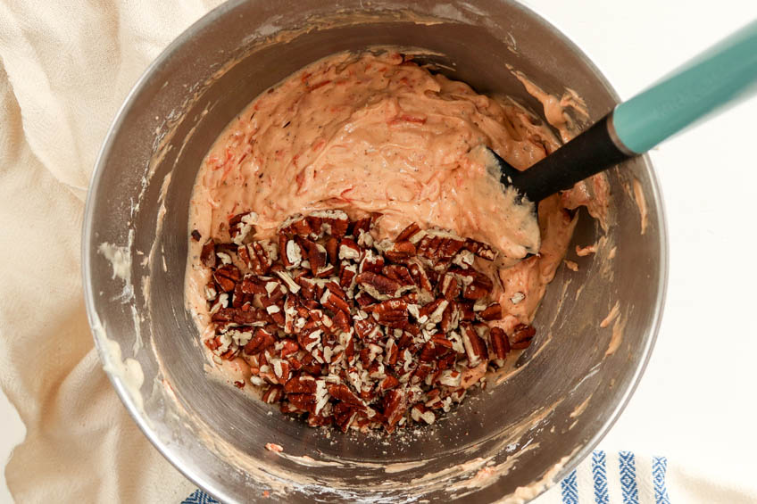 Carrot cake batter ingredients in a mixing bowl with pecans