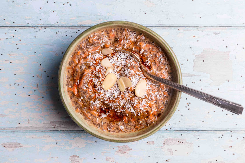 Carrot cake chia pudding in a bowl topped with shredded coconut and sliced almonds