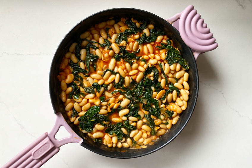 Beans and kale in a thick tomato sauce in a skillet