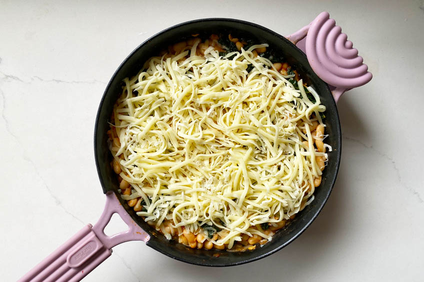 Beans and kale topped with mozzarella in a skillet