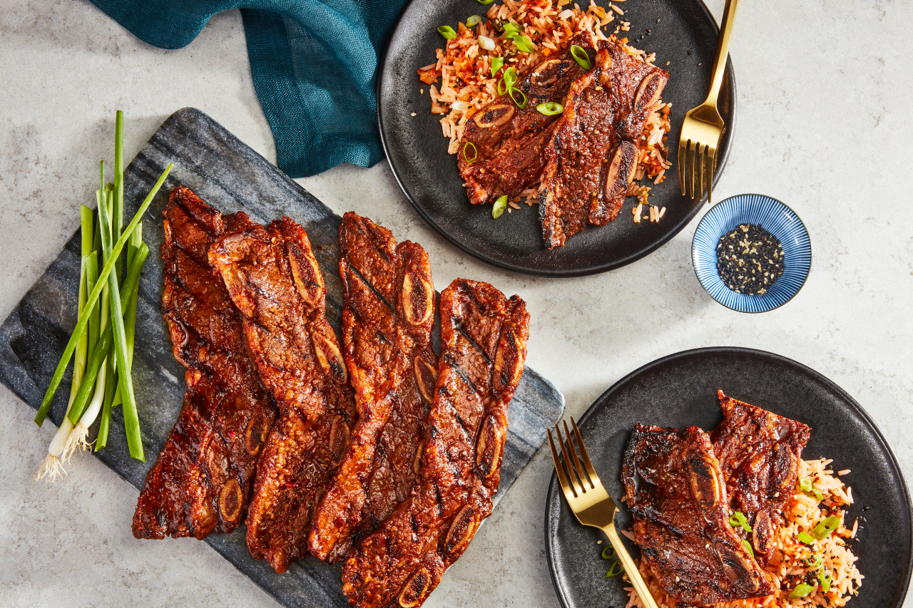 Korean BBQ beef short ribs on a cutting board and two plates.