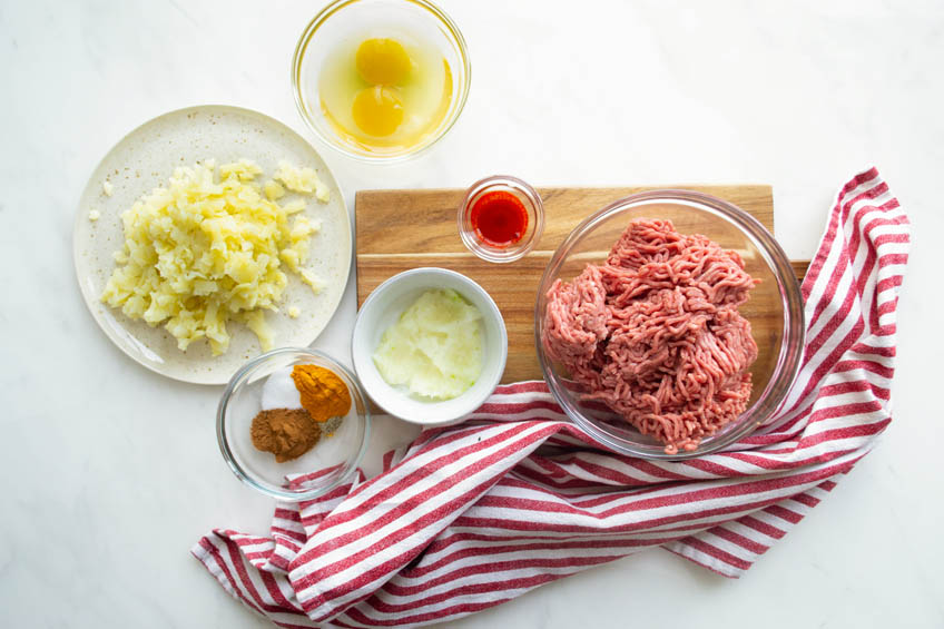 A flat lay of the ingredients to make beef kotlet: ground beef, spices and onions