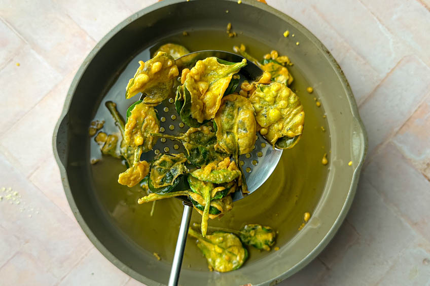 Spinach pakora being fried in oil