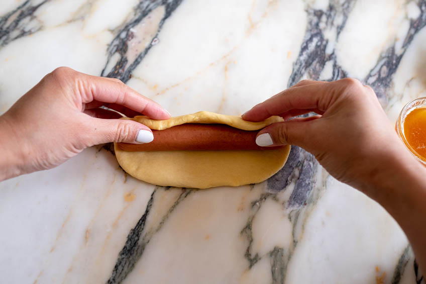 A hotdog being wrapped up in dough