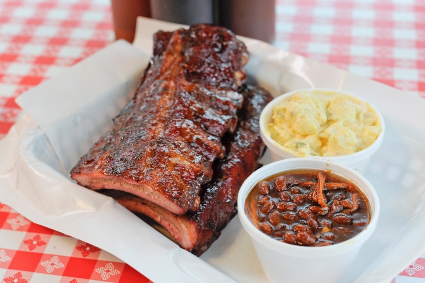 A rack of barbecue ribs with a side of beans and potato salad from Bogart's in St Louis, Missouri
