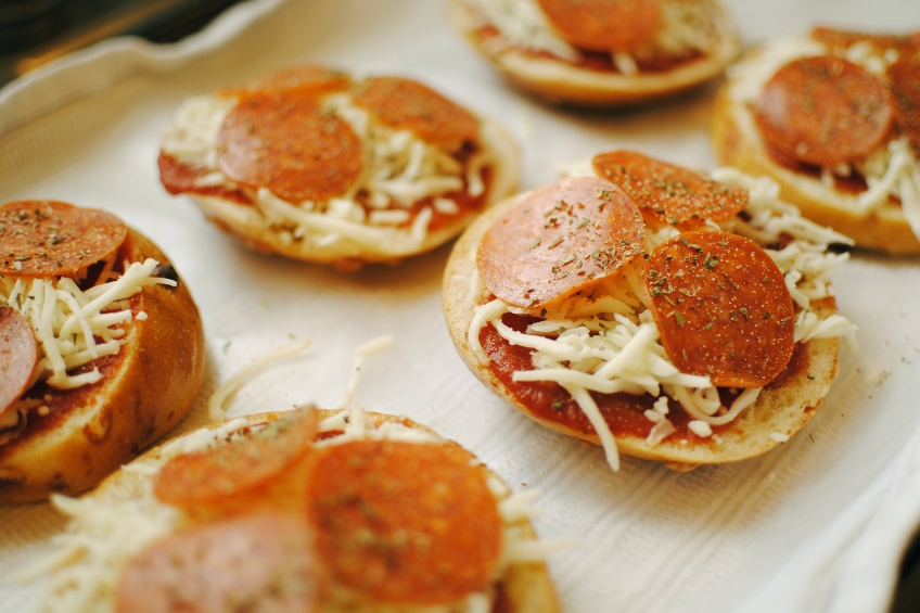 Pizza bagels topped with sauce, cheese and pepperoni ready to go into the oven