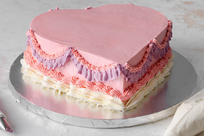A heart-shaped cake with ruffled icing on the sides