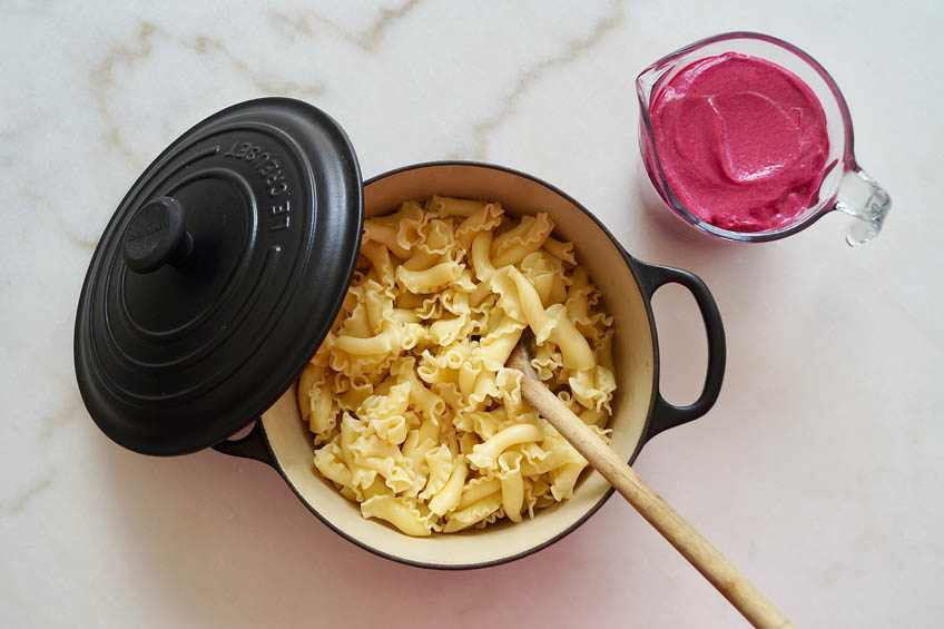 A pot of pasta alongside a creamy pink beet sauce