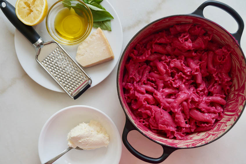 Pasta coated in bright pink beet sauce in a Dutch oven