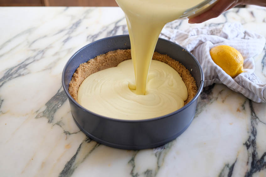 Cottage cheese cheesecake being poured into a graham cracker crust