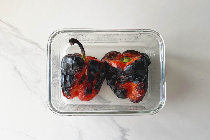 Charred red peppers in a container