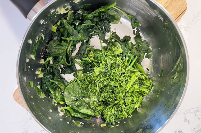 Spinach and herbs sauteing in a pot