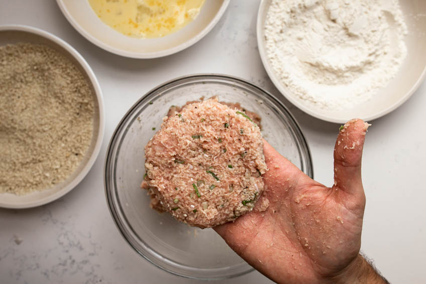 Chicken patty being shaped by hand